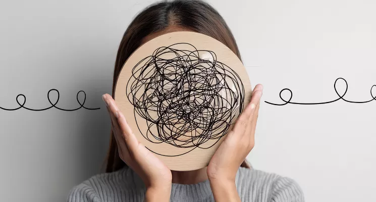 Mujer sosteniendo un dibujo de garabatos delante de la cabeza, estrés y salud mental