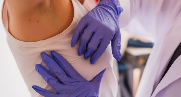 Profesional sanitaria con guantes revisando la piel del brazo de una paciente